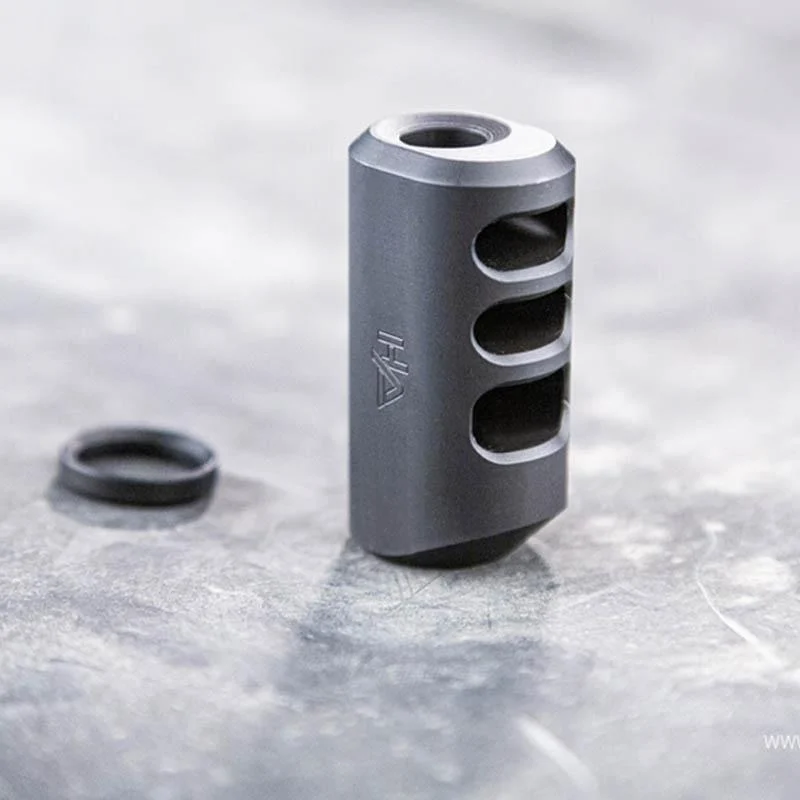 Close-up of a 1/2x28 9mm pistol compensator attached to a semi-automatic handgun, reducing recoil and improving accuracy.